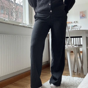 Svarta kostymbyxor med vita ränder från Mexx - Säljer ett par svarta kostymbyxor från Mexx med vita tunna ränder. Byxorna har normal passform och raka ben.