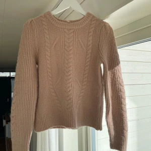 Beige stickad tröja med kabelmönster - Mysig beige stickad tröja med stickat mönster framtill. Hyfsat tjock och väldigt fin till vintern! 