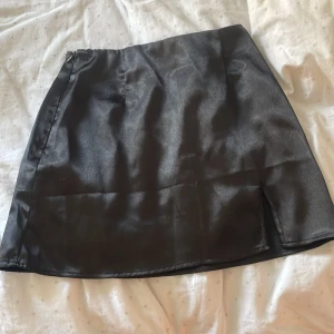 Svart satinkjol - Säljer en svart, glansig satinkjol med kort längd och enkel design. Kjolen har en liten slits och en   dragkedja på sidan. Perfekt till sommaren 🌸💕