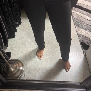 Svarta kostymbyxor med normal passform - Snygga svarta kostymbyxor med klassisk design och normal passform. Byxorna har medel midja, raka ben och stängs med dragkedja och knapp. Perfekta för en stilren look och passar till många olika outfits.