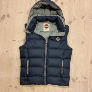 Mörkblå Colmar väst med luva  - Säjer en riktigt fet colmar väst med luva med tjockt och skönt material. Den e i topp skick och passar perfekt till kalla dagar eller sommar kvällar. Den är i storlek M men kan även passar S. Skriv för frågor eller likande 🤗
