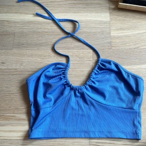 Blå ribbad bikiniöverdel från SHEIN - Säljer en blå bikiniöverdel från SHEIN i storlek XS. Toppen har ribbat material och smala knytband i nacken. Enkel och stilren design som passar perfekt till sommaren.