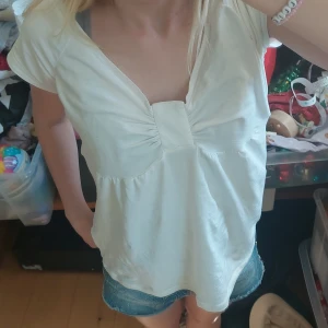 Vit v-ringad y2k  topp från Replay - Säljer en vit v-ringad topp från Replay med rynkade detaljer vid bysten. Toppen har korta ärmar och är tillverkad i mjuk bomull, perfekt för en avslappnad stil. Helt ny köpt!