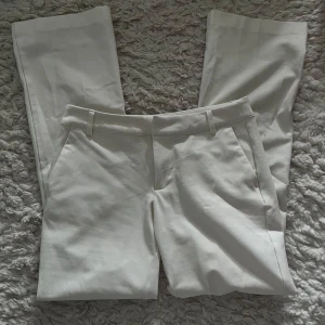 Vita kostymbyxor från BikBok low waist - Snygga vita kostymbyxor från BikBok med raka ben och klassisk passform. Byxorna har hällor för bälte, snedställda fickor fram och dekorativa fickor bak. Perfekta för en stilren look. Nypris: 499kr