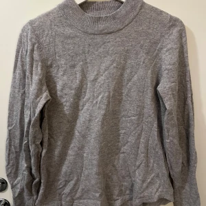 Grå polotröja storlek S från Gina tricot  - Mysig grå polotröja med lång ärm och ribbad krage. Tunt stickad från Gina tricot 