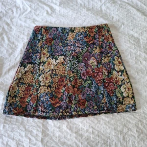 Blommig kortkjol i gobelängtyg - Underbar vintageinspirerad minikjol med blommönster💛 Perfekt till våren! Köpt här på plick:) Tyget är ganska styvt och inte särskilt stretchigt.
