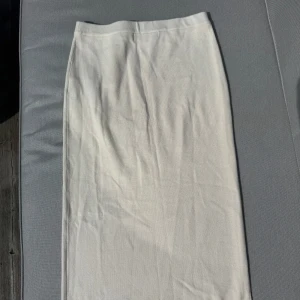 Vit kjol Vero Moda - Säljer en  vit långkjol från Vero Moda. Kjolen har en rak passform och är tillverkad i ett mjukt material i storlek L. Kjolen går att ha både hög och lågmidjat