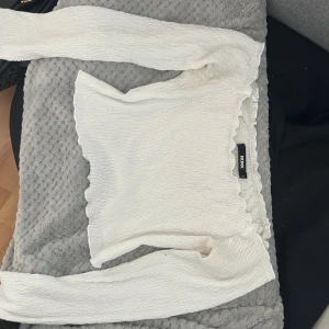 Vit off shoulder topp  - Säljer en vit långärmad off shoulder topp från Bik Bok med mjukt och stretchigt material. Toppen har en kroppsnära passform och är perfekt att styla till olika outfits. Superfin och enkel att matcha!