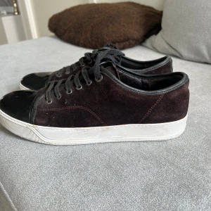 Svarta lanvins  - Säljer ett par svarta/bruna  lanvins med ovandel i mocka och detaljer i blankt skinn på tån. Skorna har svarta snören och vit platt sula. Perfekta för en stilren vardagslook. Priset är inte helt fast i sten 