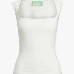 Vit ärmlös linnetopp från JJXX - Säljer en stilren vit linnetopp från JJXX med fyrkantig ringning. Toppen är ärmlös och har en tight passform, perfekt att matcha med jeans eller kjol. Enkel och fräsch design som passar till många tillfällen.
