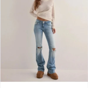 Lågmidjade Ljusblå bootcut jeans med slitningar - Snygga ljusblå bootcut jeans med slitningar vid knäna. De har en klassisk femficksdesign och en låg midja.jag har klippt av dom längst ner så dom passar mig som är 160! Knappast aldrig använda, slutsålda och  ny pris 699