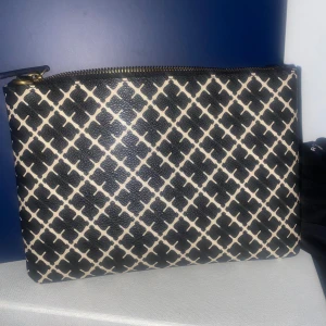 Svart och beige kuvertväska med mönster - Säljer en snygg kuvertväska i svart och beige från Madeleine Birger. Väskan är köpt för ca en månad sen, kvitto och dustbag medföljer.  Och pris kan diskuteras🫶🏽