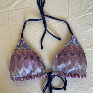 Bikiniöverdel med knytband - Snygg bikiniöverdel med ett färgglatt mönster i blått, rosa och lila. Den har justerbara knytband i mörkblått runt nacken och ryggen. Perfekt för en dag på stranden eller vid poolen!💙