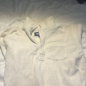 Vit frottétröja från Nikben - Säljer en vit frottétröja från Nikben med krage och knappdetalj framtill. Tröjan har en bröstficka och långa ärmar, perfekt för en avslappnad stil. Passar bra till både vardag och chill.(nypris 1300kr)