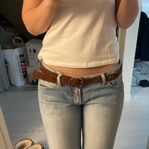 Brunt flätat bälte - Säljer ett snyggt brunt flätat bälte med rund spänne.  Passar bra till jeans och andra byxor. Jag har vanligtvis W.28/29. Går att använda om man har större  eller mindre då man kan knäppa den vart som.