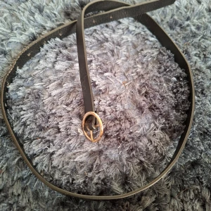 Svart bälte med gulddetalj - Snyggt svart bälte med en elegant guldfärgad ringdetalj. Perfekt för att ge en stilren touch till din outfit. Bältet är smalt och passar bra till både jeans och klänningar.