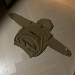 Essentials hoodie  - Säljer en snygg brun hoodie från Essentials med text på bröstet och ärmen. Den har en klassisk ficka. Perfekt för en baggy stil.        Pris ej hugget i sten👀