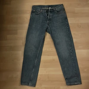 Blå jeans från Weekday - Säljer ett par blå jeans från Weekday i modellen Barrel Relaxed Tapered. De har en avslappnad passform med avsmalnande ben och klassisk femficksdesign. Perfekta för en stilren och bekväm look.