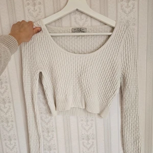 Vit topp - Säljer en stilren vit ribbad tröja från Chiquelle. Den är croppad med långa ärmar och har en rund halsringning. Perfekt för en vår- eller sommaroutfit. Passar till både jeans och kjol!🩷