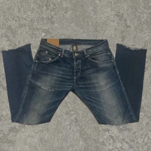 Mörkblå jeans från Dondup - Snygga mörkblå jeans från Dondup med en klassisk femficksdesign och diskreta slitningar. Jeansen har en knappgylf. tillverkade i ett slitstarkt denimtyg och längst nere vid benen är det en cutoff design. Perfekta för en avslappnad stil. Pris går att diskutera vid snabb affär💯