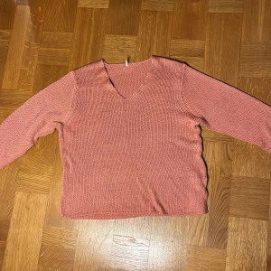 Rostfärgad stickad tröja från Soyaconcept - Säljer en snygg rostfärgad stickad tröja från Soyaconcept. Tröjan har en v-ringad hals och långa ärmar, perfekt för kyligare dagar. Den är mjuk och bekväm, idealisk för både vardag och avslappnade tillfällen.