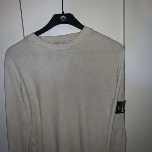 Vit tröja från Calvin Klein Jeans - Säljer en stilren vit tröja från Calvin Klein Jeans. Tröjan har långa ärmar och en rund halsringning. Perfekt för en avslappnad och trendig look. Är xs men sitter som M.