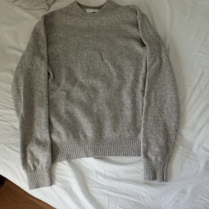 Grå tröja i merinoull från Vailent - Säljer en stilren grå tröja från Vailent i mjuk merinoull. Tröjan har en klassisk rund hals och långa ärmar med ribbade muddar. Perfekt för kyliga dagar och enkel att matcha med olika outfits. Använd några gånger inga defekter. Pris kan diskuteras 