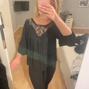Svart blus med spetsdetaljer - Elegant svart blus med vackra spetsdetaljer vid halsringningen. Blusen har långa ärmar som går att dra upp till trekvarts som jag har på bild och en lös passform som ger en stilren look. ☺️