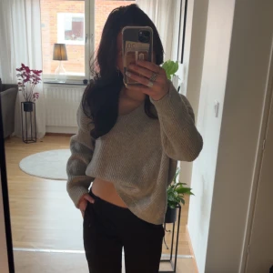 Grå stickad tröja med v-ringning - Säljer en mysig grå stickad tröja med v-ringning. Tröjan har långa ärmar och en avslappnad passform, perfekt för kyligare dagar. Den ribbade strukturen ger en stilren look.✨ Osäker på nypriset! Säljer då den inte används! (Storlek M då jag ville ha en lite oversized look) 💞