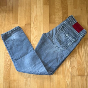 True Religion Jeans - Säljer ett par gråa jeans från True Religion. Använda fåtal gånger i nytt skick. Storlek 34 men passar även med bälte till mig som brukar ha 30/32. 
