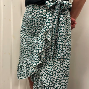 Blommig volangkjol  - Jättefin blommig volangkjol. Dold zip up vid höften samt två band för att göra en rosett. 