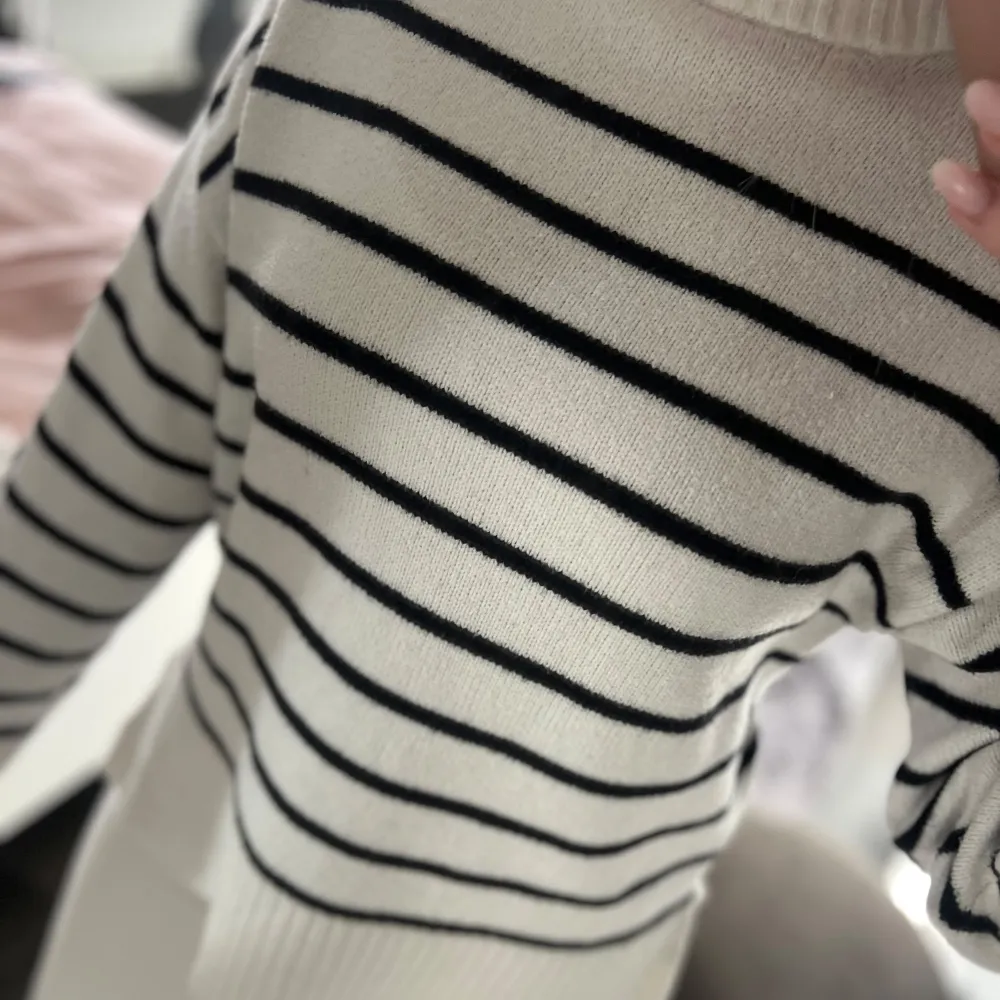 Säljer en snygg vit stickad tröja med svarta ränder. Tröjan har en rund hals och långa ärmar med ribbade muddar💗. Neuletakit & Villapaidat.