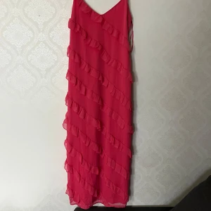 Rosa klänning från Gina Tricot - Säljer en snygg rosa klänning från Gina Tricot med volangdetaljer. Klänningen har smala axelband, en v-ringad design och en lägre rygg💕