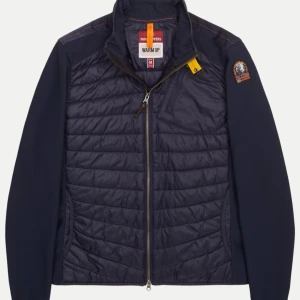 Mörkblå jacka från Parajumpers - Snygg mörkblå jacka från Parajumpers med quiltad design och dragkedja framtill. Jackan har en cool patch på ärmen och en gul detalj vid kragen. Perfekt för kyligare dagar. Nypris 3700kr mitt pris 1800 knappt använd.