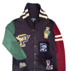 Ralph Lauren Cardigan - Säljer en unik flerfärgad kofta från Polo Ralph Lauren med broderade detaljer och applikationer. Den är lite nopprig men kör maskin innan jag skickar iväg så den ser ut som ny 🙌 Hör av dig vid fler frågor
