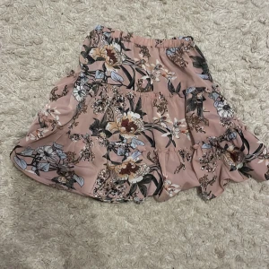 Blommig kjol från Shein - Söt blommig kjol från Shein i rosa med volanger. Perfekt för en somrig look med sitt lätta och luftiga material. Den har ett elastiskt midjeband för extra komfort.