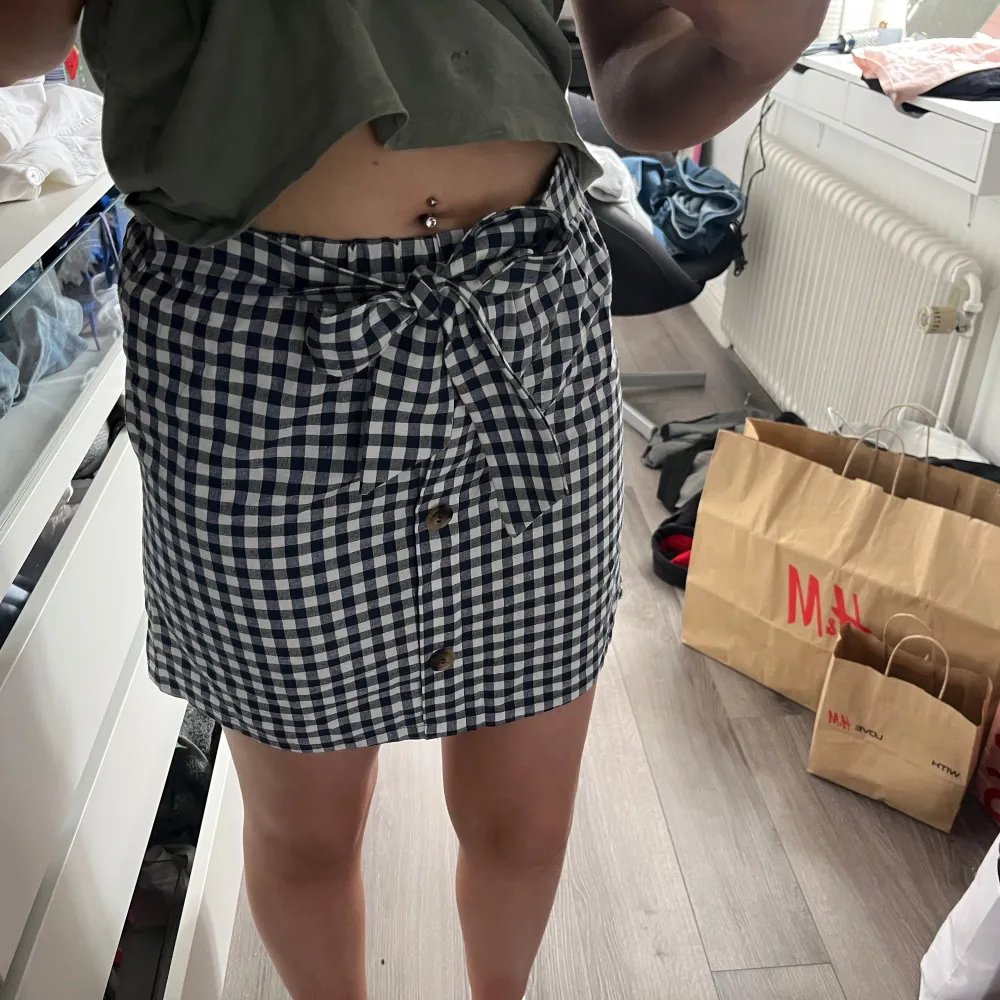 Snygg rutig kjol från Shein i blått och vitt. Kjolen har knappar framtill och ett knytband i midjan för extra stil. Perfekt för en trendig look!. Hameet.