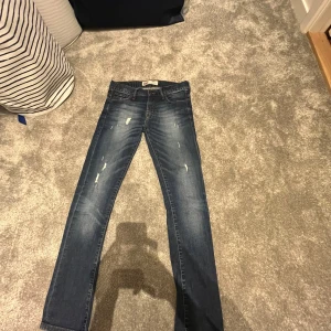 Levis 520 jeans - STORLEKEN ÄR 14 MEN ANATAR ATT DET ÄR TYP FÖR DEM SOM ÄR RUNT 170. Snygga Levis 520 jeans i en klassisk blå tvätt med slitna detaljer. De har en knappgylf och femficksdesign. Perfekta för en avslappnad stil.