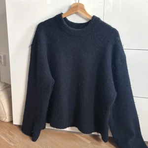 Marinblå stickad tröja från Gina Tricot - Säljer en stilren marinblå stickad tröja från Gina Tricot i storlek S. Tröjan har en klassisk rund hals och långa armar, perfekt för sommarkvällar. 