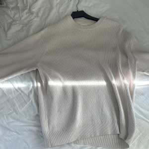 Beige ribbad tröja - Säljer en stilren beige ribbad tröja med långa ärmar. Perfekt för en avslappnad look. Tröjan har en klassisk passform och rund halsringning.