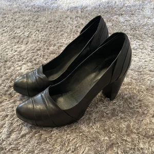 Svarta pumps - Eleganta svarta pumps i skinn med en bekväm klack. Perfekta för en stilren look. Hög klack, men inte för hög utan är fortfarande bekväma🖤
