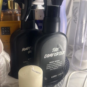 The Comforter Body Spray från Lush - The Comforter Body Spray från Lush i en svart sprayflaska. Den har en fruktig och söt doft med inslag av cypress och svartvinbär. Perfekt för att ge en mysig känsla. Flaskan rymmer 200 ml.