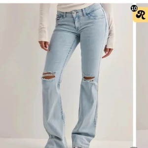 Ljusblå bootcut jeans med slitningar - Snygga ljusblå bootcut jeans med slitningar på knäna och broderade detaljer på bakfickorna. Perfekta för en avslappnad stil med en touch av edge. De har en låg midja och klassisk femficksdesign. Säljer igen då hon ångrade sig