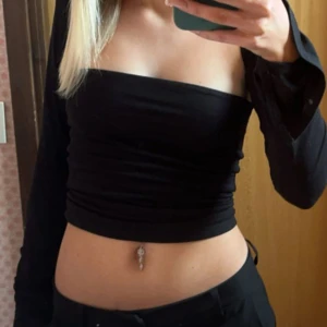 Svart offshoulder topp - Snygg svart offshoulder topp med långa ärmar. Perfekt för en stilren och trendig look. Toppen är tight och framhäver figuren på ett elegant sätt.