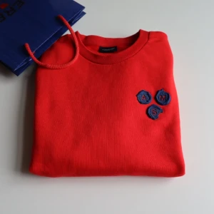 Scotch&soda cardigan  -  röd tröja med en broderad detalj på bröstet. Tröjan har långa ärmar och en rund halsringning. Orginalpriset var 1 289 kr säljer för 849 för att den inte har varit använd 