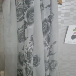 Grå sjal/ halsduk - Säljer en elegant grå halsduk / sjal med ett vackert rosmönster. Perfekt för en stilren look. Sjalen har en mjuk och flödande design som ger en romantisk känsla.