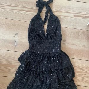 Svart glittrig klänning - Snygg svart klänning med glittriga detaljer och volanger, storlek S/M, prislapp kvar💗