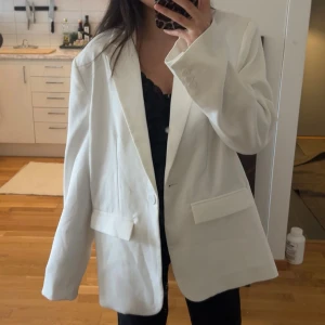 Oversize kavaj NA-KD - Snygg vit kavaj från NA-KD med klassisk design. Den har långa ärmar, axelvaddar, en bred krage med slag, knappstängningar, framfickor med lock och en rak oversized passform. Använd någon enstaka gång. Skulle säga att den passar från stl 32-36. Ordinariepris: 799kr