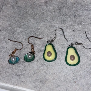 Örhängen med avokado och snäckskal - Två par unika örhängen. Ett par med avokadoform i grönt och gult, och ett par med snäckskal i turkos med pärldetalj. Perfekta för att ge en lekfull touch till din stil.,oanvända