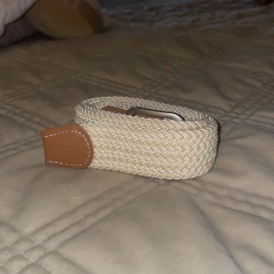 Beige flätat bälte - Snyggt beige flätat bälte med bruna läderdetaljer och silverfärgat spänne. Köpt för 150. 95 cm men går att sträcka ut. 